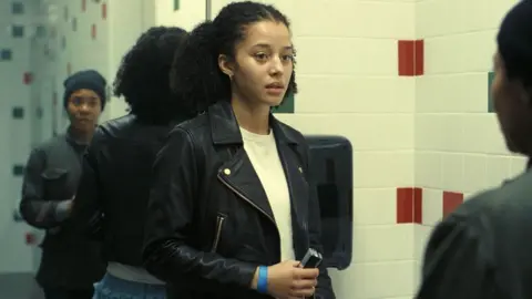 Warner Bros Chase Infiniti and Regina Hall standing in a bathroom, in one scene from One Battle After Another