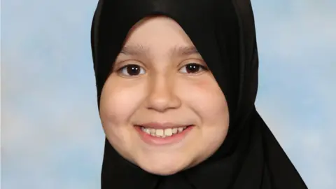 Surrey Police Sara Sharif smiling at the camera. She is wearing a hijab and looking directly at the camera.