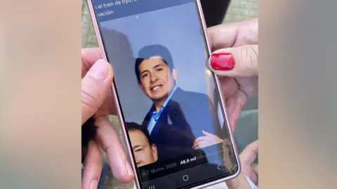 BBC/Marianne Baisn&eacute;e An image of someone is shown on their phone wearing a blue jacket with dark hair