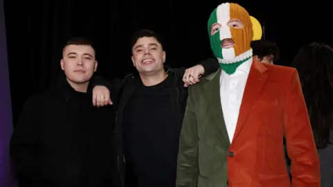 Getty Images Three men stand next to each other. One is wearing an Irish tricolour balaclava and suit.
