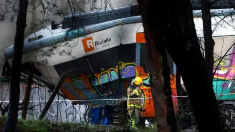 EPA A twisted Rodalie train carriage is seen on the morning after it derailed, as a firefighter inspects the scene