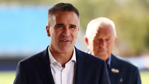 Getty Images Premier of South Australia Peter Malinauskas, wearing a navy suit and a white shirt, speaks to media
