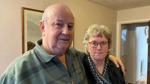 An older couple standing arm in arm