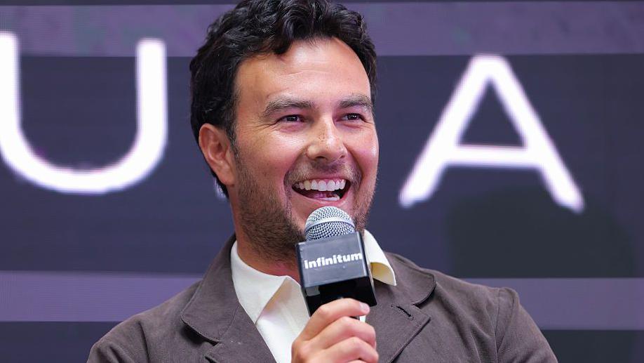 Sergio Perez speaking into a microphone at a Cadillac news conference in 2025