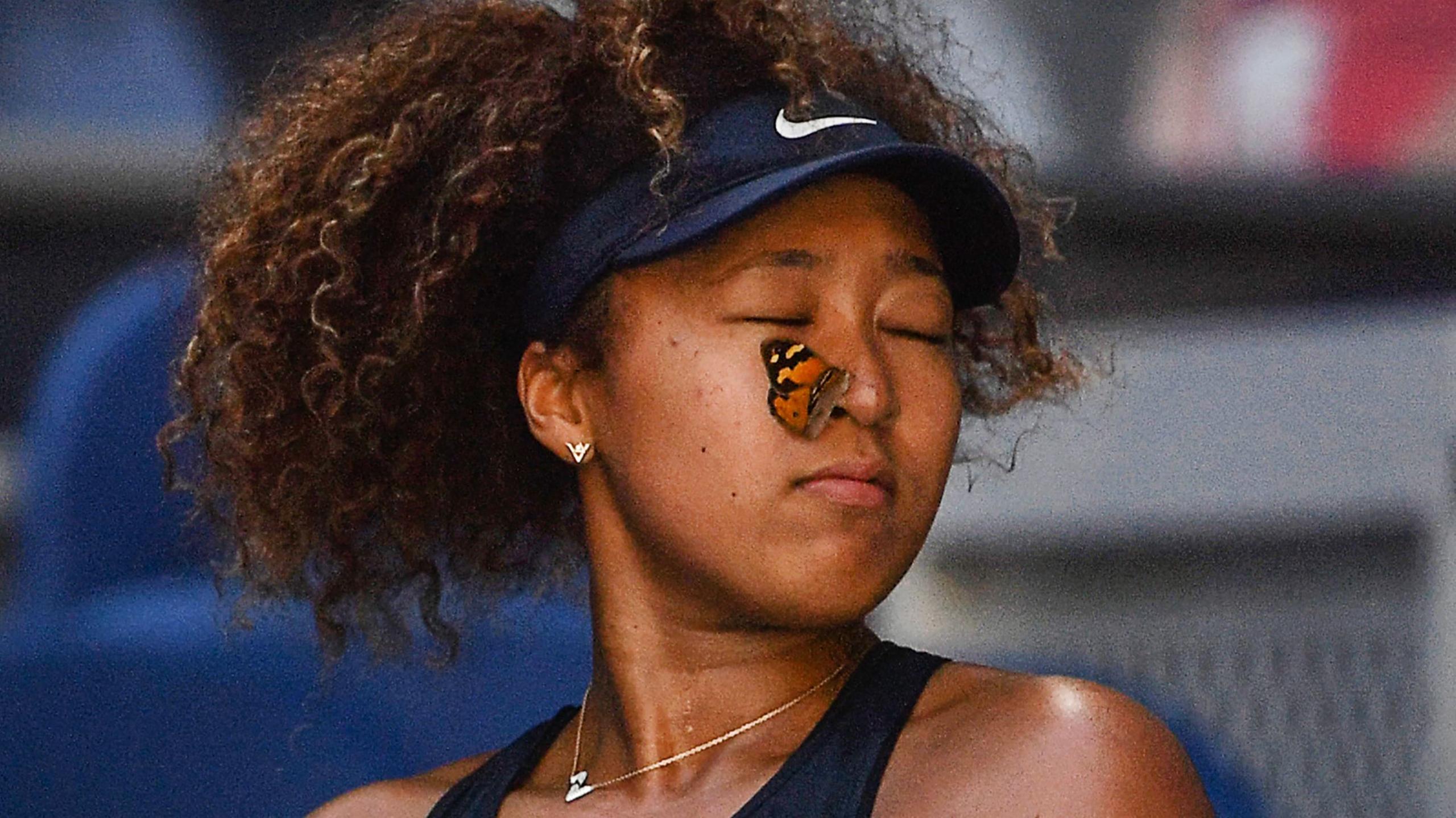 A butterfly lands on Naomi Osaka's face during a match in 2021