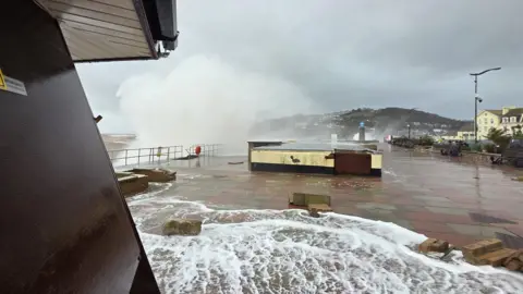 BBC/Johnny Rutherford Debris are seen over Teignmouth seafront as waves batter the coast.