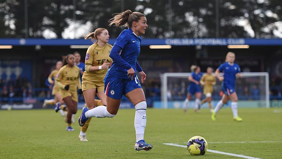 Johanna Rytting Kaneryd, of Chelsea, in action during the Women's FA Cup fourth round match against Crystal Palace. She has blonde hair, tied back, and is looking in front of her as she runs with the ball. Several other players can be seen in the background.