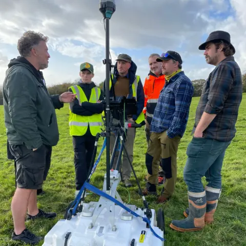 Swansea University The ArchaeoMargam project team meet to discuss their survey work, standing around the ground penetrating radar device