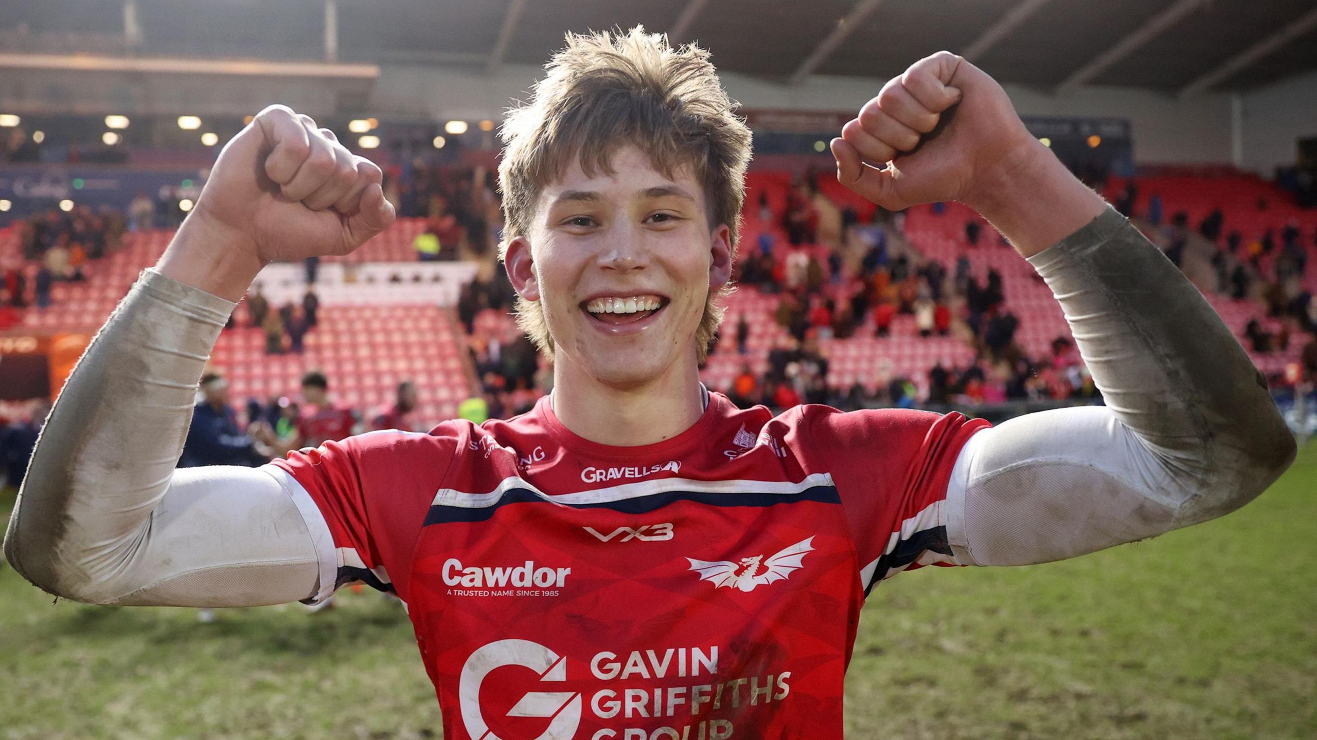 Wing Ellis Mee, smiles and raises too clenched fists in triumph