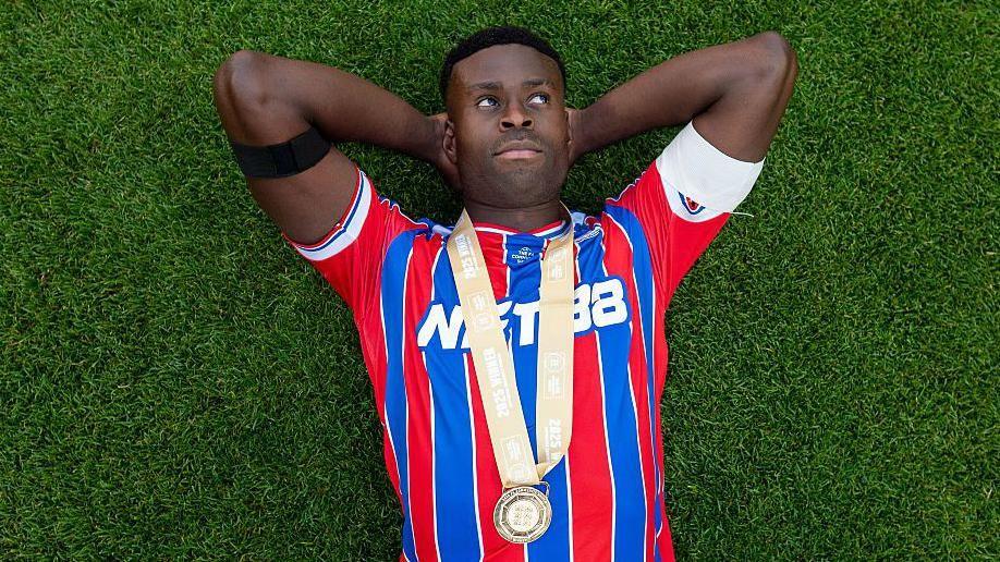 Marc Guehi lies on the Wembley pitch staring up at the sky with his winners medal around his neck