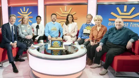 (left to right) Charlie Stayt, Carol Kirkwood, Naga Munchetty, Jon Kay, Sally Nugent, Francis Wilson, Debbie Rix and Russell Grant with a commemorative cake, on the red sofa as BBC Breakfast celebrate its 40th anniversary with a special show and guests at MediaCityUK, Salford. Picture date: Tuesday January 17, 2023.