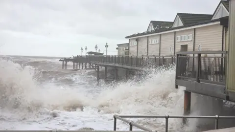 BBC/Johnny Rutherford Waves are seen battering a wooden pier.