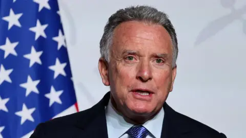 Reuters An image of the US Special Envoy to the Middle East, Steve Witkoff, speaking in front of the American Flag visible to the left.