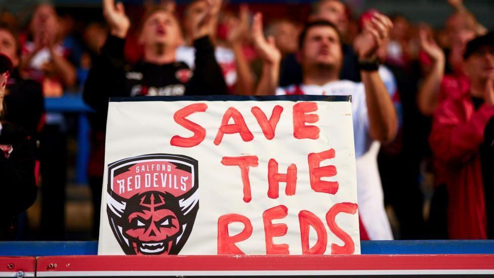 A 'Save The Reds' placard during a Salford Red Devils fixture in 2025