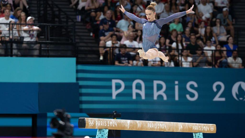 Alice Kinsella does a split leap on beam