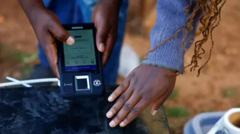 Reuters A polling agent scans a box containing electoral materials with a Biometric Voter Verification Machine (BVVM) at a polling station