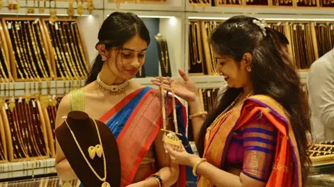 Getty Images Two women looking at gold on display at a gold jewellery store