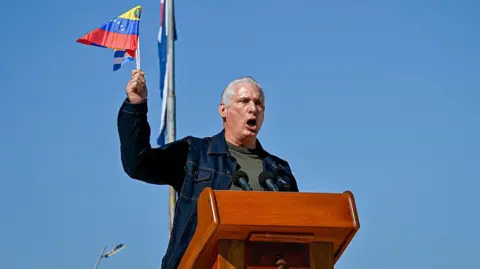 AFP via Getty Images Cuba's President Miguel Diaz-Canel delivers a speech as he waves a Venezuelan national flag in support of Venezuelan leader Nicolas Maduro in Havana on 3 January 2026.
