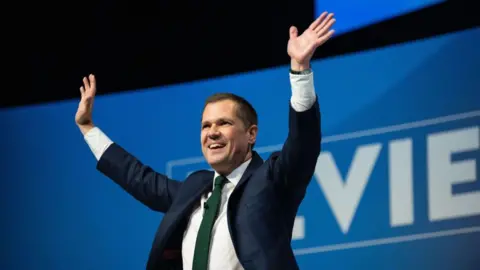 Getty Images Robert Jenrick waving on stage after delivering his speech to the Conservative Party conference in Birmingham