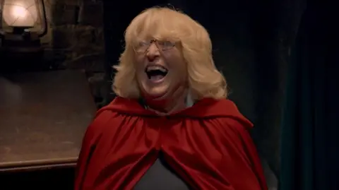 Fiona in her read cloak laughing wildly in the turret after being revealed as the secret traitor