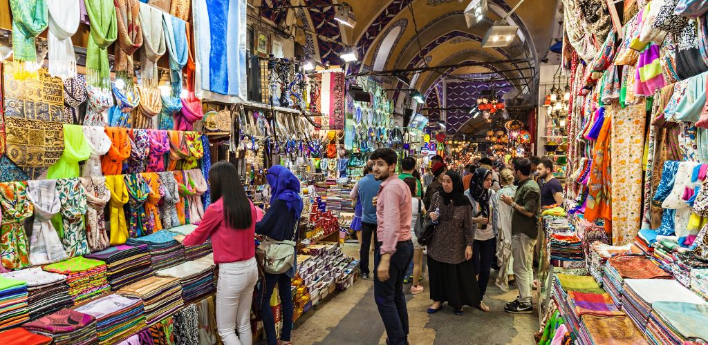 A bazaar with colorful fabric for sale in crowded customers.
