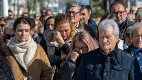 EPA/Shutterstock People gather to observe a minute of silence in memory of the victims of the train collision that occurred on 18 January, in Punta Umbria, Huelva, Spain, on 20 January 2026