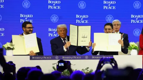 Reuters Bahrain's Minister of the Prime Minister&rsquo;s Court Shaikh Isa bin Salman bin Hamad Al Khalifa, U.S. President Donald Trump and Morocco's Foreign Minister Nasser Bourita hold signed Charter of the Board of Peace, as the takes part in a charter announcement for his Board of Peace initiative aimed at resolving global conflicts, alongside the 56th annual World Economic Forum (WEF), in Davos, Switzerland, January 22, 2026.