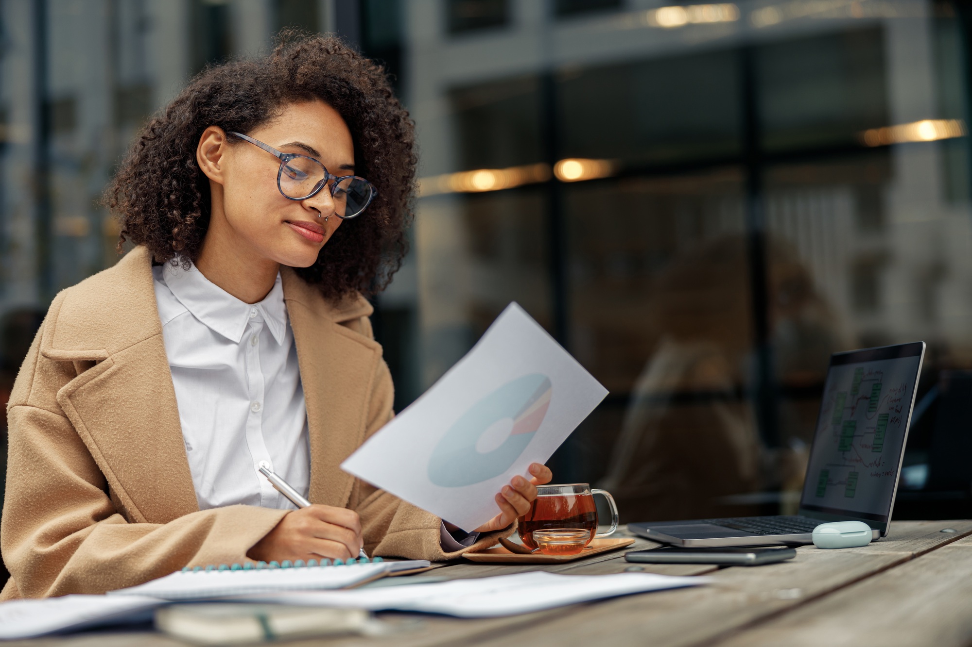Afro american woman freelancer working remotely while sitting on cafe terrace