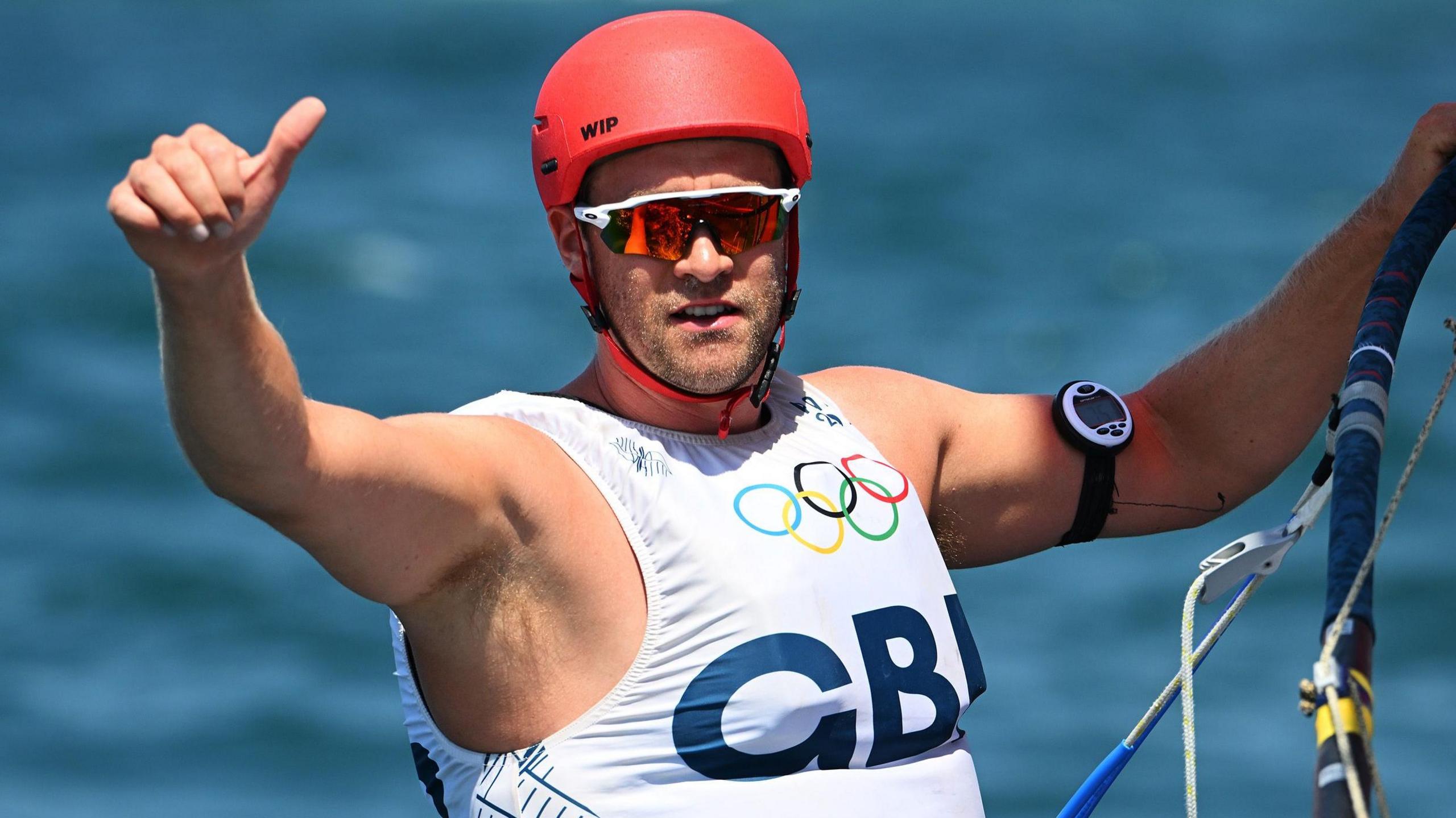 Sam Sills gives a thumbs up while windsurfing