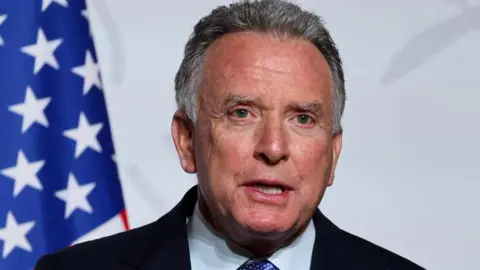 Reuters An image of the US Special Envoy to the Middle East, Steve Witkoff, speaking in front of the American Flag visible to the left.