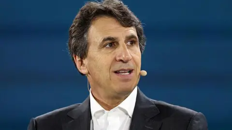 Getty Images An image of businessman Marc Rowan looking to the right with a microphone attached to his face, while dressed in a black suit and sat in front of a blue backdrop.