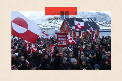Getty Images People hold Greenlandic flags and placards as they gather by the United States Consulate to march
