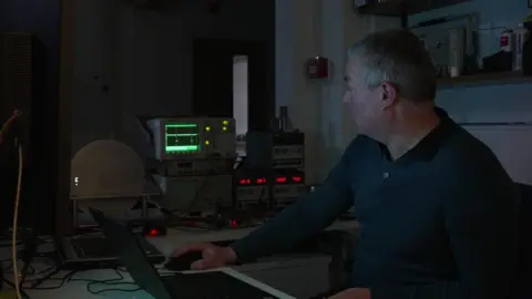 Gary Toms, a Chartered Engineer in the Innovation Centre at the University sat in a room surrounded by monitors staring at a circle with a light on it