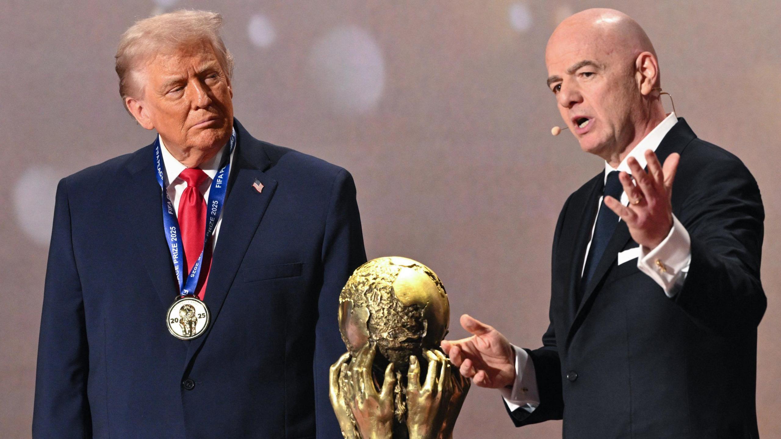 US President Donald Trump (left) and Fifa president Gianni Infantino (right) either side of the World Cup trophy at the 2026 tournament draw