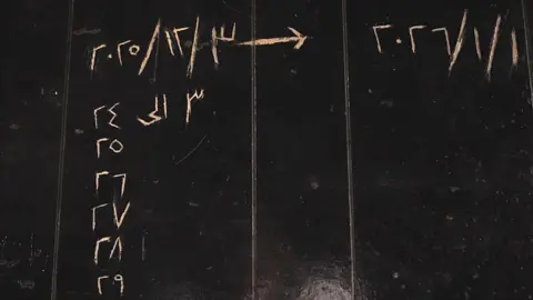 Liam Weir / BBC Black-painted wall with dates in Arabic scratched into it