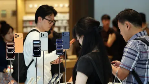 News1 People examining iPhones at an Apple store
