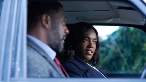 Mosaku, who is playing the role of Det Sgt Catherine Halliday in Luther, is pictured in the passenger seat of a car next to the character of Luther, played by Idris Elba.