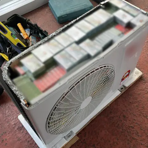 Singapore Immigration and Checkpoints Authority Boxes of vaping supplies are neatly stacked inside an empty air-conditioner fan unit. The boxes have been blurred out by authorities.
