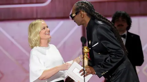Getty Images Amy Poehler and Snoop Dogg laugh together onstage at the 83rd Golden Globe Awards in Beverly Hills