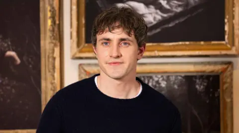 PA Media Paul Mescal - a man with dark hair and a black jumper, standing in what appears to be an art gallery.