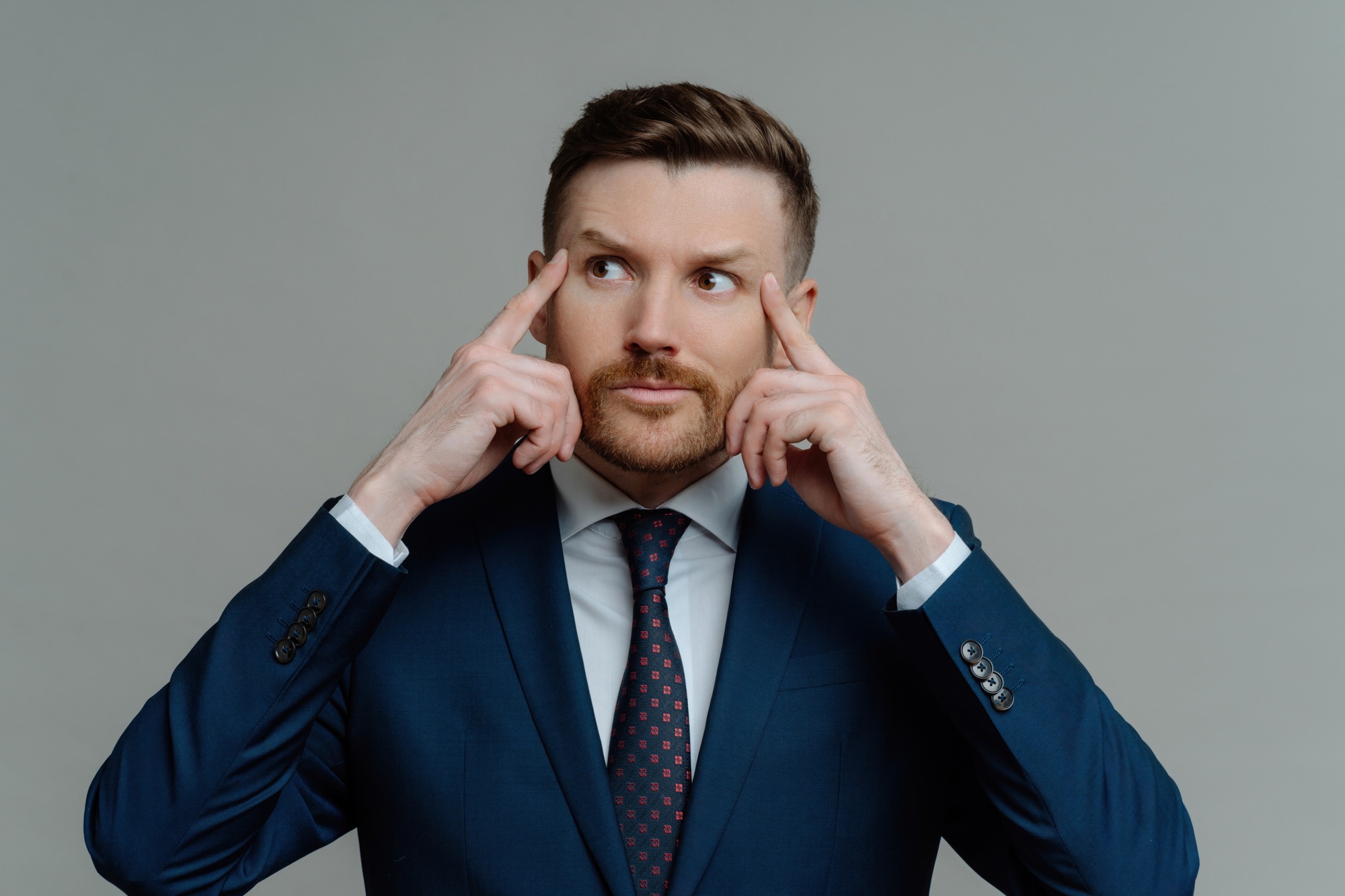Motivated businessman preps for conference, thoughtful, formal attire, grey background