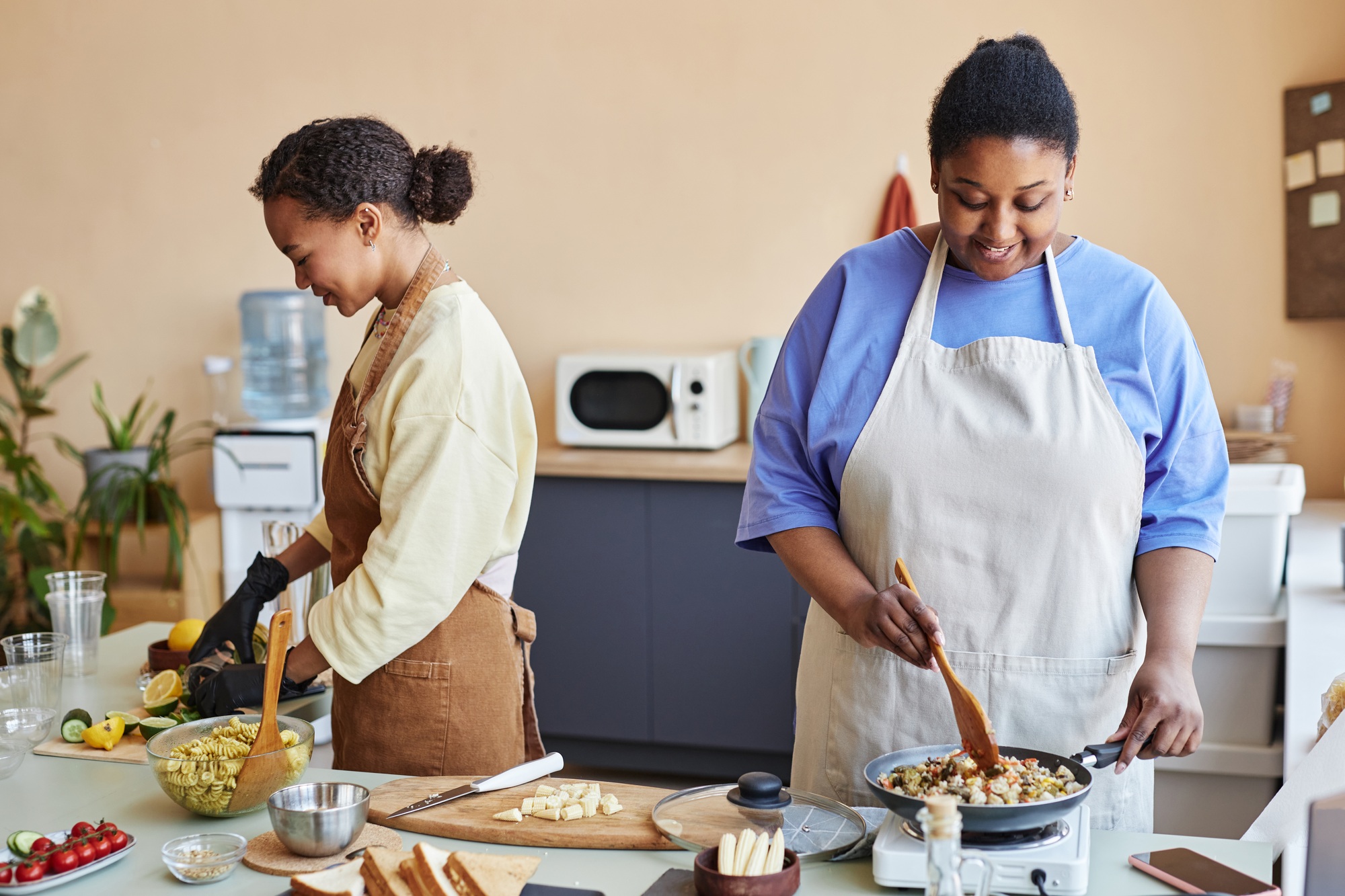 Two African American women doing food prep in kitchen cooking together