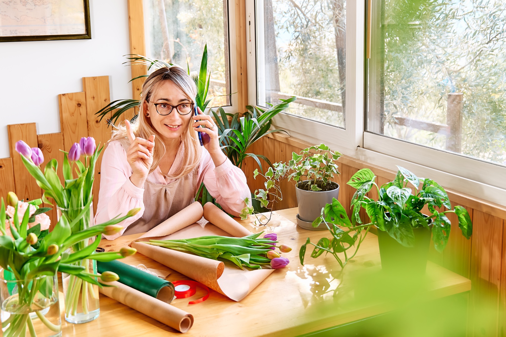 Woman florist in flower shop taking order by mobile phone. Social media for small business.