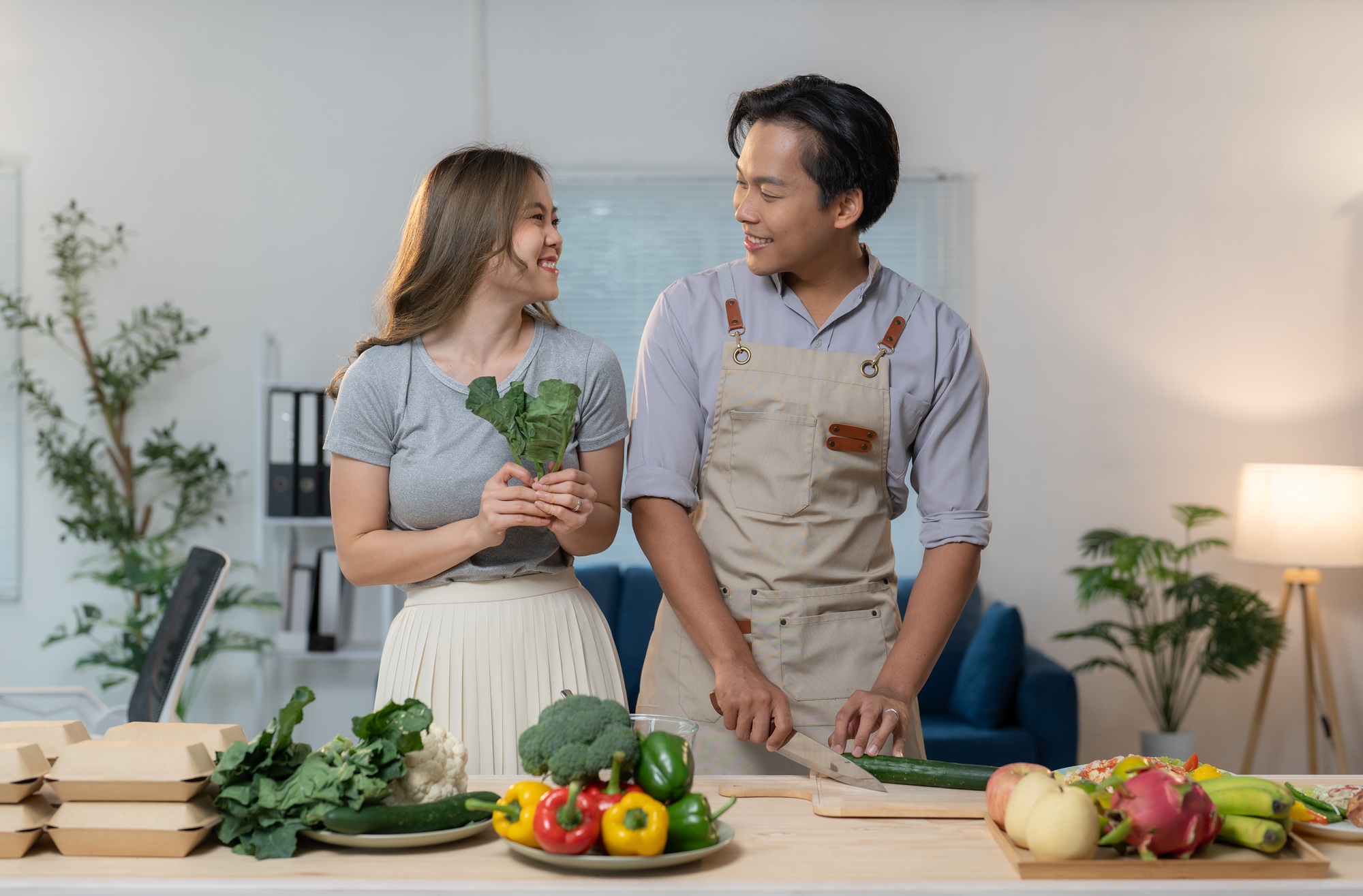 Young asian couple preparing fresh vegetables and fruits for a healthy meal kit business, working to