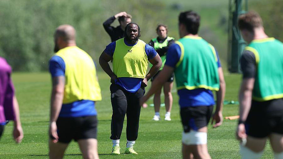 Beno Obano (centre) standing with his hands on his hips during a training session for Bath at Farleigh House