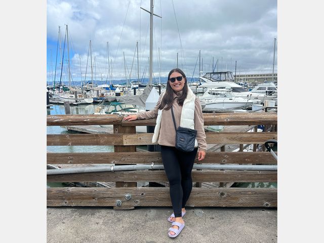 Image may contain: Water, Waterfront, Clothing, Pants, Accessories, Bag, Handbag, Person, Teen, and Sitting