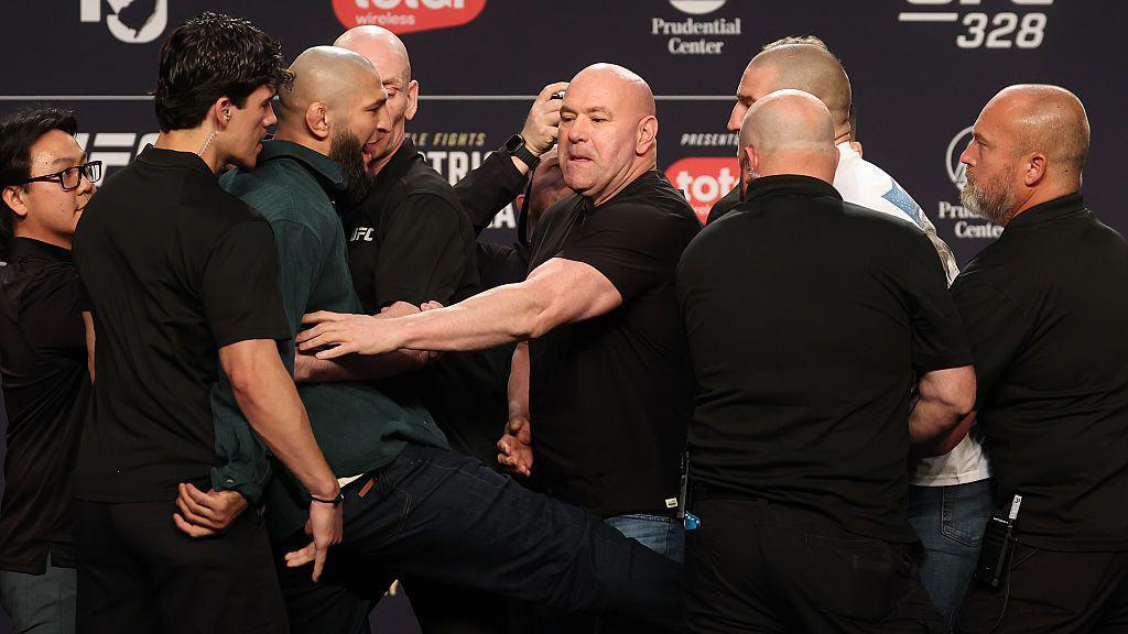 Khamzat Chimaev kicks Sean Strickland at the UFC 328 news conference