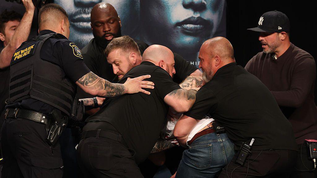 Security and armed police step in to separate Sean Strickland and Khamzat Chimaev at the UFC 328 news conference