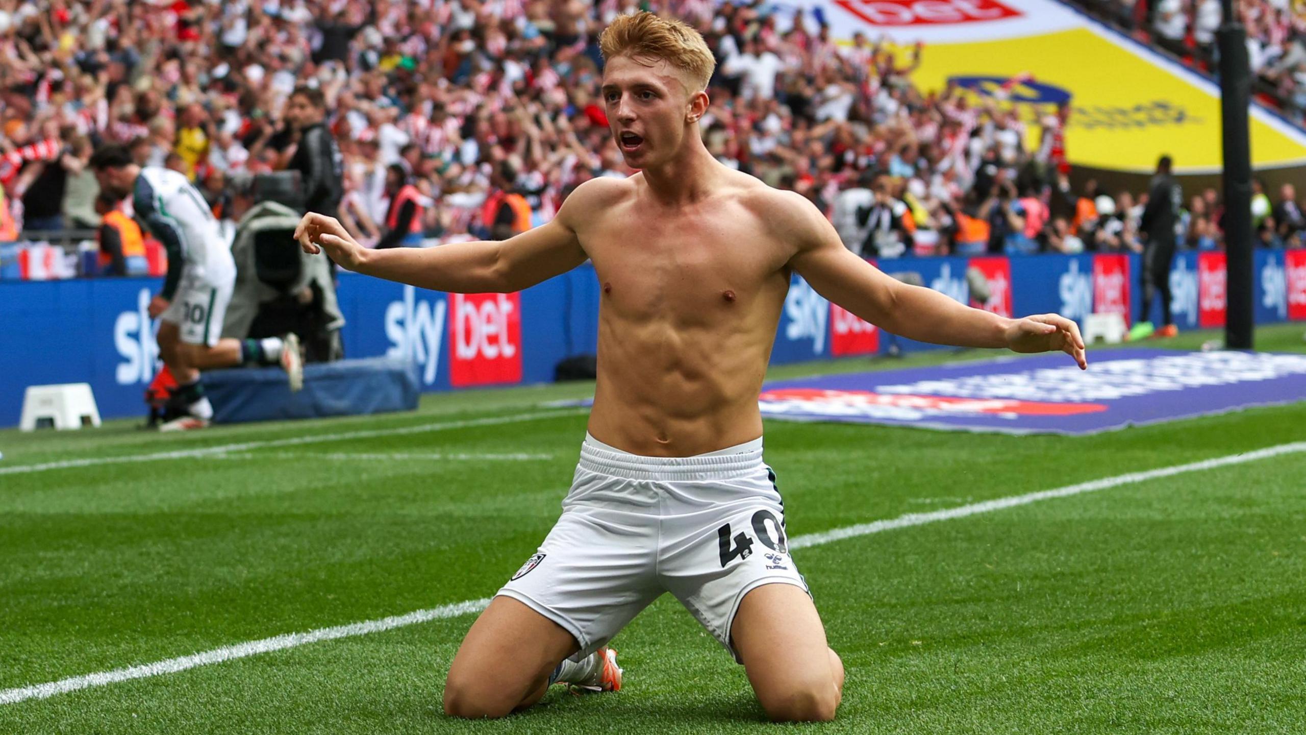 Sunderland's Tom Watson without a shirt on slides on his knees with his arms outstretched to celebrate scoring the winning goal in the play-off final against Sheffield United