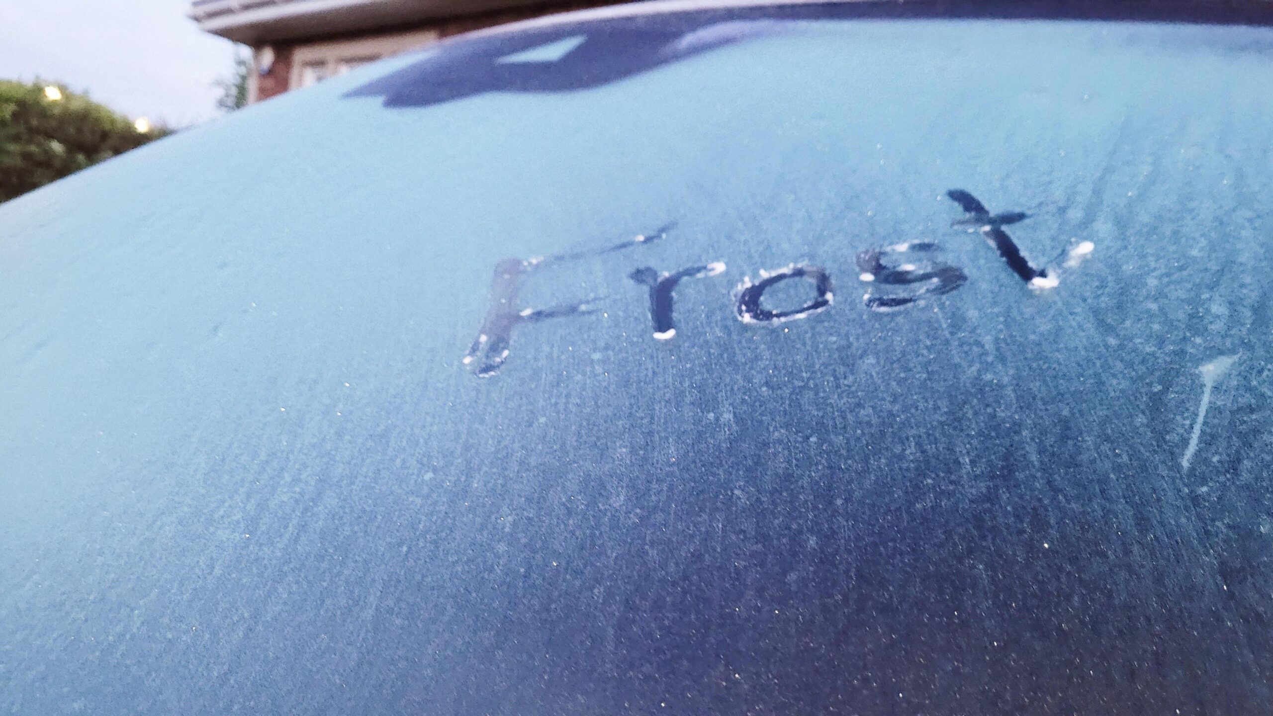 Photograph of a frozen windscreen with the word 'frost' drawn into it.